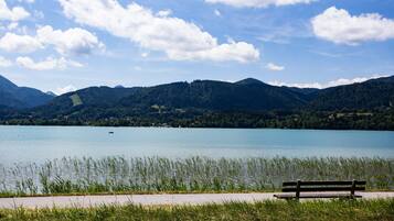 Un banc au bord d’un lac, avec des montagnes en arrière-plan.