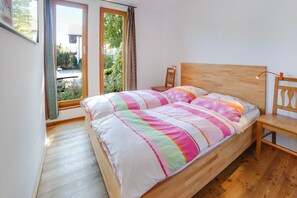 Una camera da letto con un letto in legno, un comodino, una sedia e una finestra con tende.
