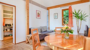 A modern interior with a wooden dining table, a sofa, and a kitchen area visible through an open door. - Holiday Apartment "Oestreich" close to Chiemsee Lake with Wi-Fi & Terrace (Chieming/ Egerer)