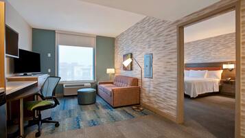 A hotel room with a desk, chair, sofa, and a bed.