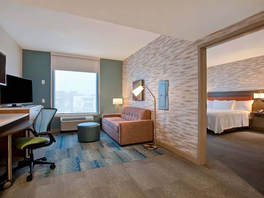 A hotel room with a desk, chair, sofa, and a bed.