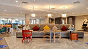 A spacious lobby with a seating area featuring a sofa, chairs, and a small table. - Home2 Suites by Hilton Carmel Indianapolis (Carmel)