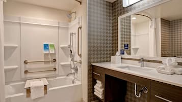 Un baño moderno con bañera, ducha, tocador y un espejo grande.