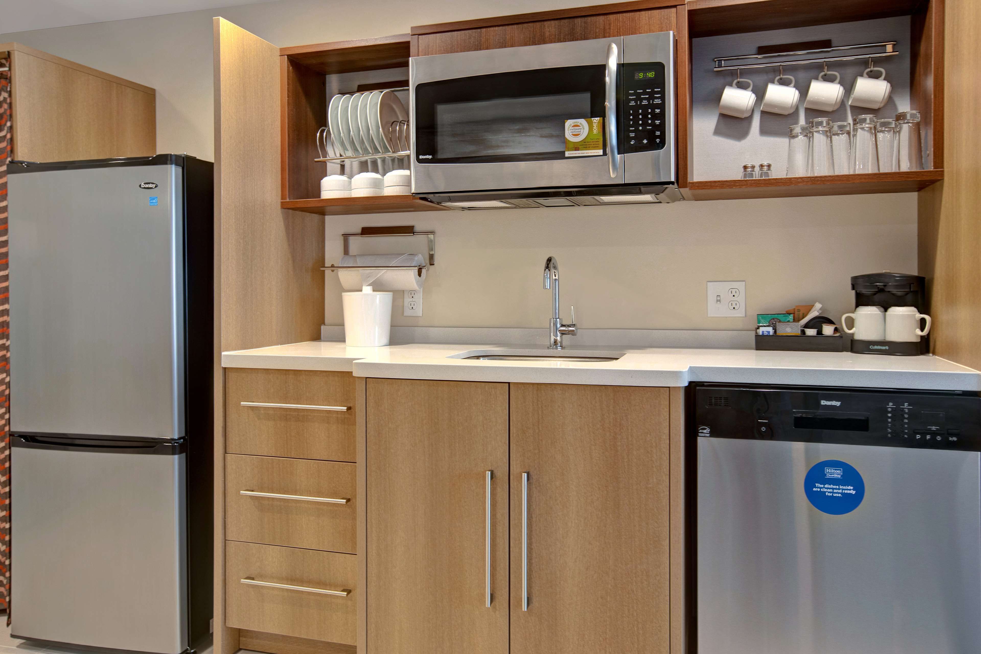 Una cocina compacta con refrigerador de acero inoxidable, microondas y lavavajillas.