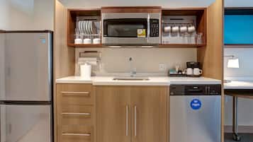 Una cocina compacta con microondas integrado, refrigerador y lavavajillas.