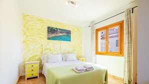 Ein Schlafzimmer mit einem Bett, einem Nachttisch, einem Fenster mit Vorhängen und einem Wandbild.