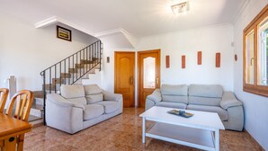 Ein Wohnzimmer mit zwei Sofas, einem Couchtisch, einer Treppe und einer Tür.