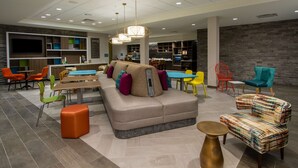A modern lounge area with a sofa, chairs, a table, and a TV screen.