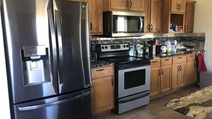 A kitchen with wooden cabinets, a stainless steel refrigerator, a microwave, an oven, and a water dispenser.