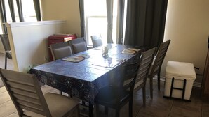 A dining area with a table covered by a patterned tablecloth, surrounded by chairs.