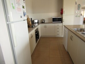 Compact kitchen with refrigerator, microwave, sink, and small oven.