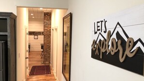 Un pasillo con piso de madera, un tapete rojo y un cartel que dice 'LET'S EXPLORE'.
