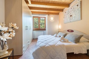 Quarto com cama, guarda-roupa de madeira, janela e um quadro na parede.