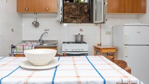 A kitchen with wooden cabinets, a stove, a sink, and a table with a bowl. - Holiday Apartment "Runcina 2" with Sea View in Green Landscape (san teodoro)