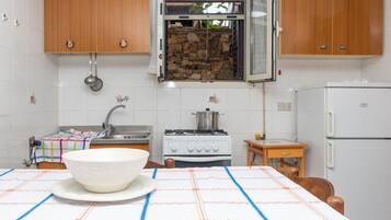 Een koelkast, een oven, een kookplaat, kookgerei, borden en bestek