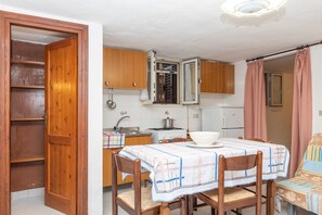 Une cuisine de taille réduite, dotée de meubles en bois, d’une cuisinière et d’un coin repas avec une table et des chaises.