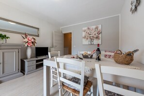 A dining area with a table set for two, a television, and a decorative vase.