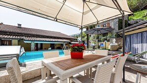 Eine Terrasss mit Pool, Korbmöbeln und einer roten Blumenvase.