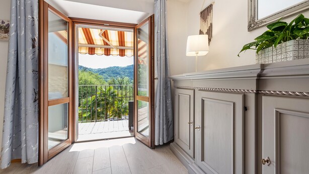 Ein Zimmer mit einer Glastür zum Balkon, einem weißen Schrank, einer Wandlampe und einem Blumentopf.