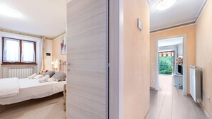 Ein Schlafzimmer mit Bett, Nachttisch, Lampe und Fenster mit Vorhängen.