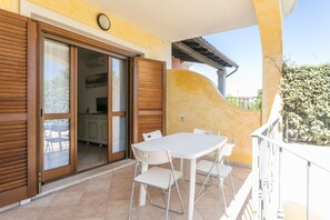 A balcony with a table and chairs, a sliding door, and a view of the interior.