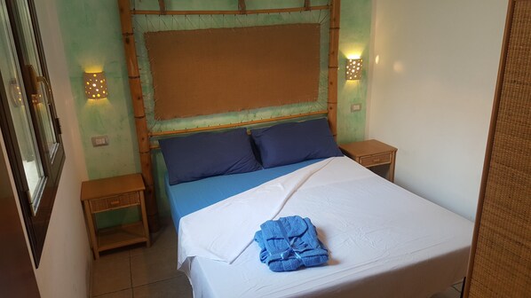 A room with a bed, two nightstands, a wall-mounted light, and a window.
