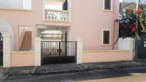 Un immeuble résidentiel doté d’une entrée sécurisée par un portail, d’un escalier et d’un balcon.