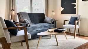 A modern living room with a grey sofa, two armchairs, a coffee table, and a large abstract painting on the wall. - NEW! Hip Downtown Pad! Walk Everywhere! (Hot Springs)