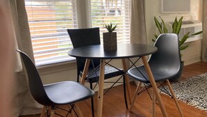 A room with a round table, two chairs, a potted plant, and a window with blinds. - NEW! Hip Downtown Pad! Walk Everywhere! (Hot Springs)
