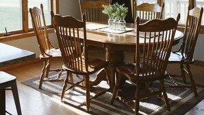 Comedor con una mesa redonda, seis sillas de madera y dos lámparas colgantes.