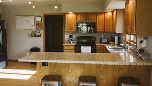Cocina con gabinetes de madera, encimera de granito y electrodomésticos de acero inoxidable.