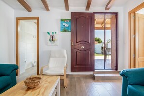 Een kamer met een houten deur, een witte stoel, een houten tafel en een groene bank.