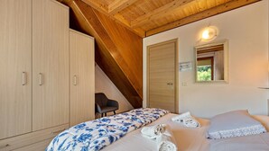 Une chambre à coucher avec un lit, une armoire en bois, une chaise et un miroir.