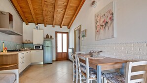 Une cuisine avec des poutres apparentes en bois au plafond, une table à manger avec des chaises, un four à micro-ondes et un réfrigérateur.