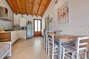 A kitchen with wooden ceiling beams, a dining table with chairs, a microwave, and a refrigerator.