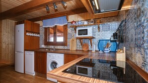 Eine kleine Küche mit Holzausstattung, einer Waschmaschine, einer Mikrowelle und einer Arbeitsplatte.