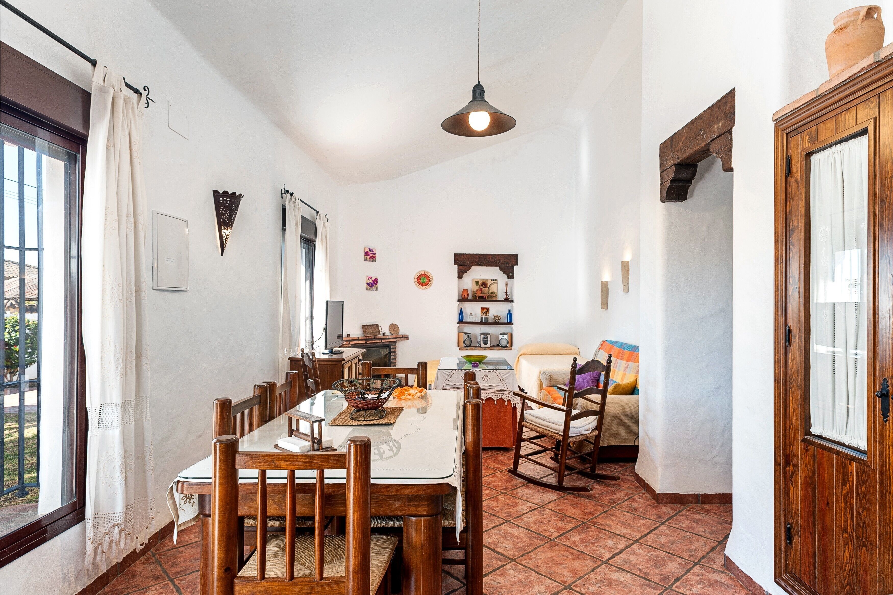 A dining area with a table, chairs, and a hanging light fixture.
