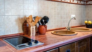 Une cuisine équipée d’un évier à deux bacs, d’une cuisinière et d’un plan de travail avec des ustensiles.