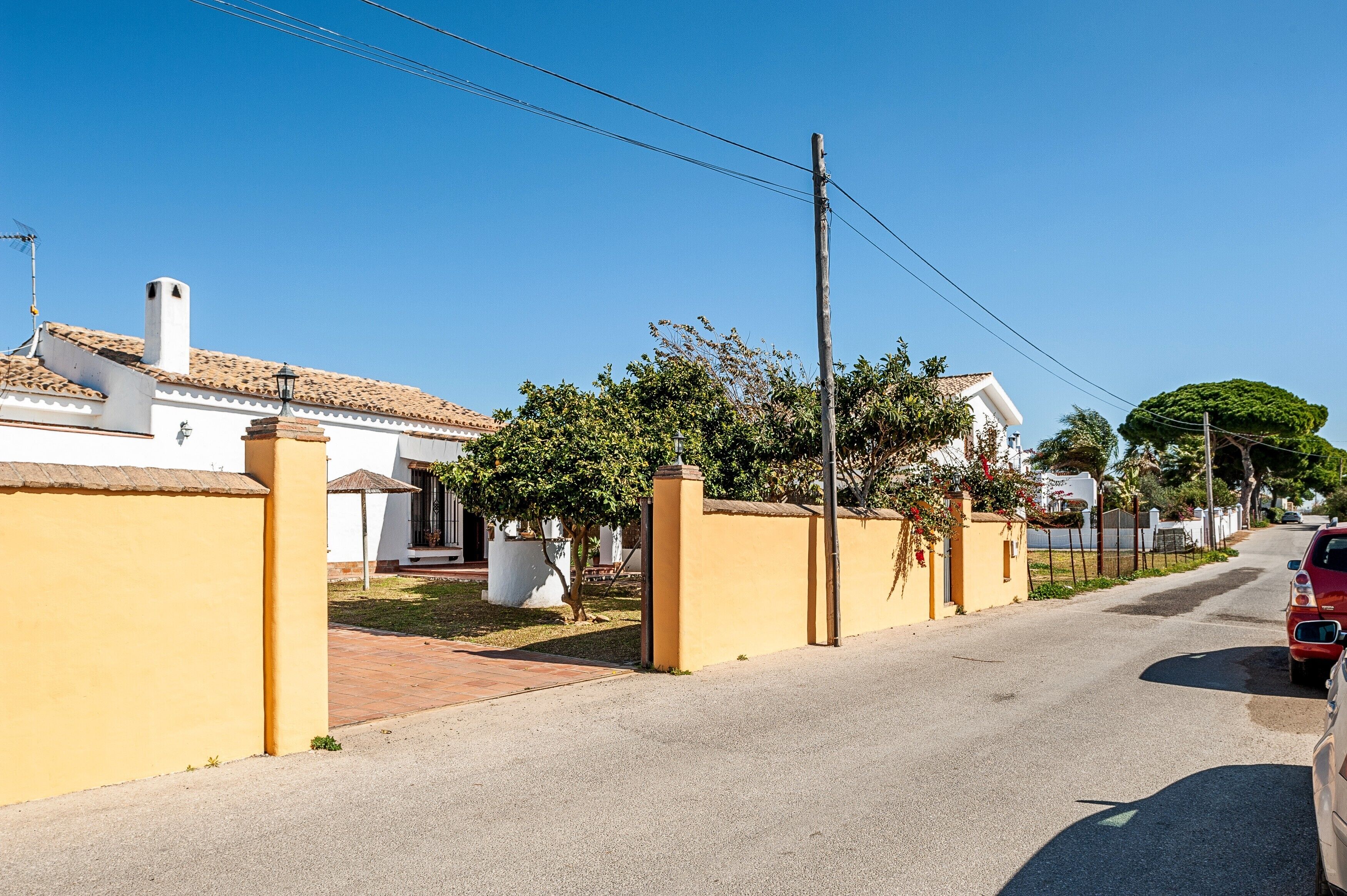 A residential street with houses, a parked car, and a clear sky.
