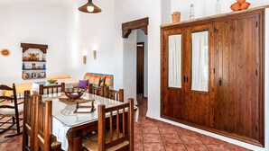 Un coin repas comprenant une table en verre, des chaises en bois, un buffet en bois et un luminaire suspendu.