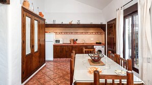 Une cuisine de taille réduite, dotée de meubles en bois, d’une table à manger et offrant une vue sur l’extérieur.