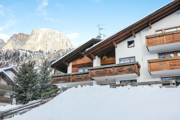 A mountain lodge with wooden balconies, a snow-covered roof, and a view of a mountain.