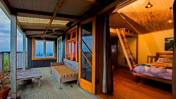 Ein gemütliches Blockhaus mit Holzbalkon, einem Bett und Blick auf die Landschaft.