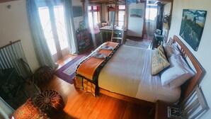 Ein geräumiges Schlafzimmer mit einem großen Bett, Holzbalkendecke und Blick ins Freie.