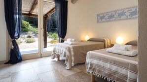 Una habitación con dos camas, un cristalero corredero y una lámpara fijada a la pared.