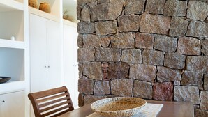Un comedor con pared de piedra, una mesa de madera, una cesta tejida y una silla.