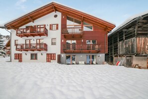 Un edificio de varios pisos con balcones, un telesilla y un paisaje nevado.