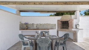An outdoor patio with a round table, chairs, a brick oven, and a stone shelf. - Comfortable Holiday Apartment "Loft Rural" with Terrace (El Soto)