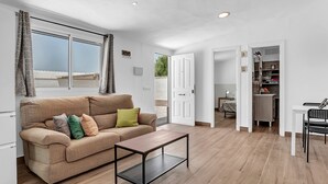 A living room with a sofa, a coffee table, and a view through a large window. - Comfortable Holiday Apartment "Loft Rural" with Terrace (El Soto)