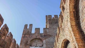 Un'antica torre in mattoni con finestre ad arco e un portale centrale, circondata da edifici simili.